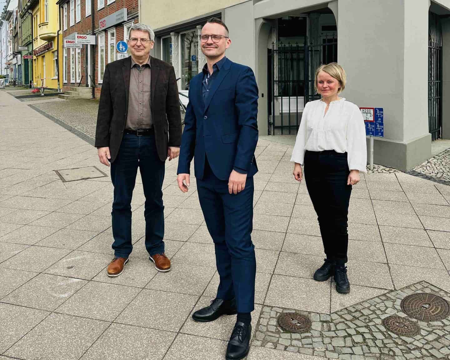 3 Menschen vor Gebäude