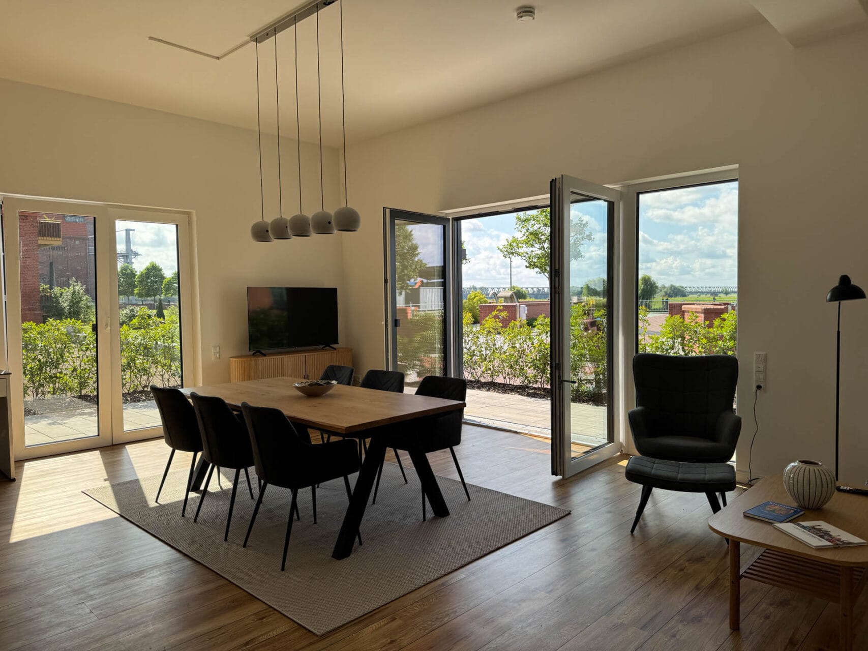 Wohnzimmer mit großem Esstisch, Fernseher und Terrasse