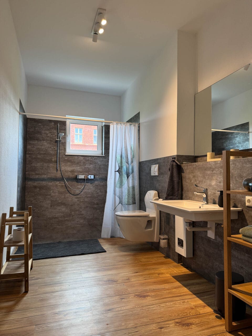Badezimmer mit ebenerdiger Dusche, WC, Waschbecken, ausklappbarer Sitz