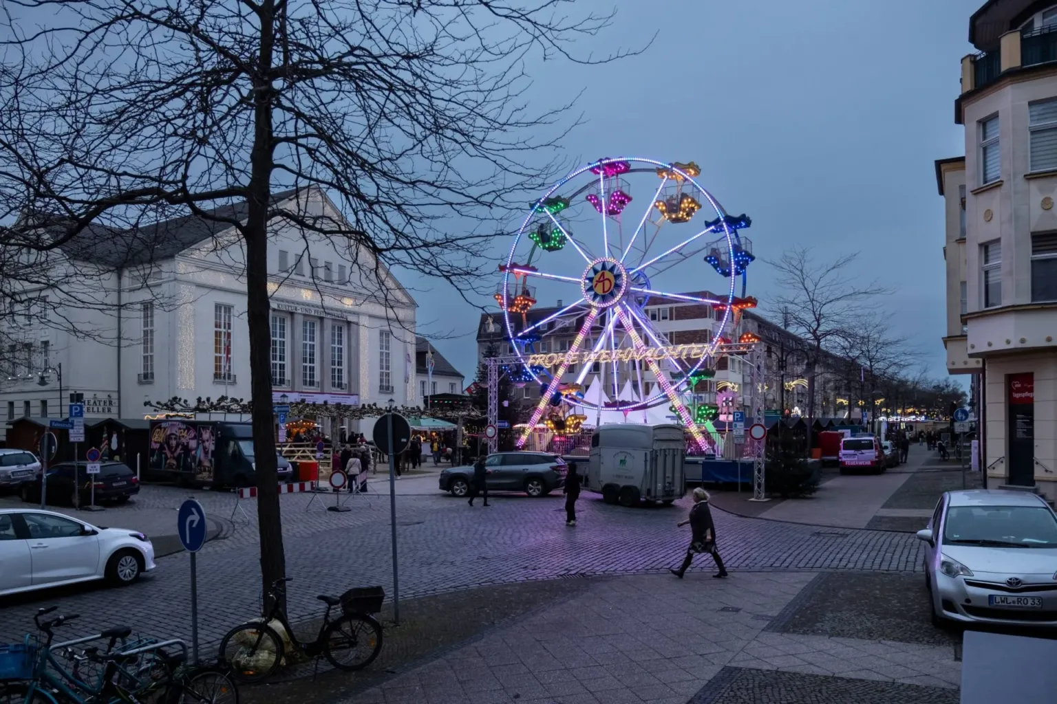 Beleuchtetes Riesenrad mit dem Schriftzug Frohe Weihnachten auf dem abendlichen Paul-Lincke-Platz
