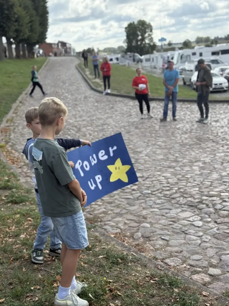 Zwei Jungs halten am Start ein Schild hoch, auf dem Power Up steht